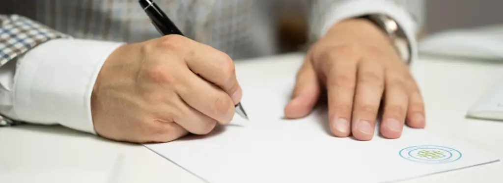 Hand mit Stift beim Unterschreiben eines Dokuments als Symbolbild für den Downloadbereich mit Satzung und Mitgliedsantrag des FK Etzbach